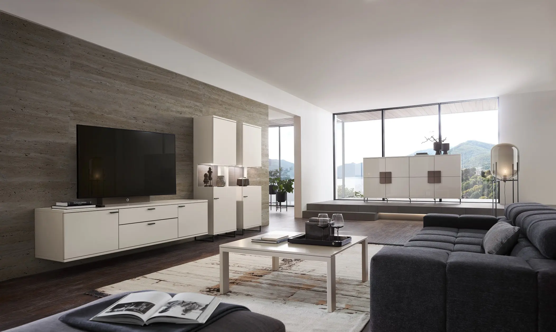 Wohnwand in sand mit hängendem Lowboard und beleuchteten Vitrinen im Wohnzimmer. Im Hintergrund passende Kommoden